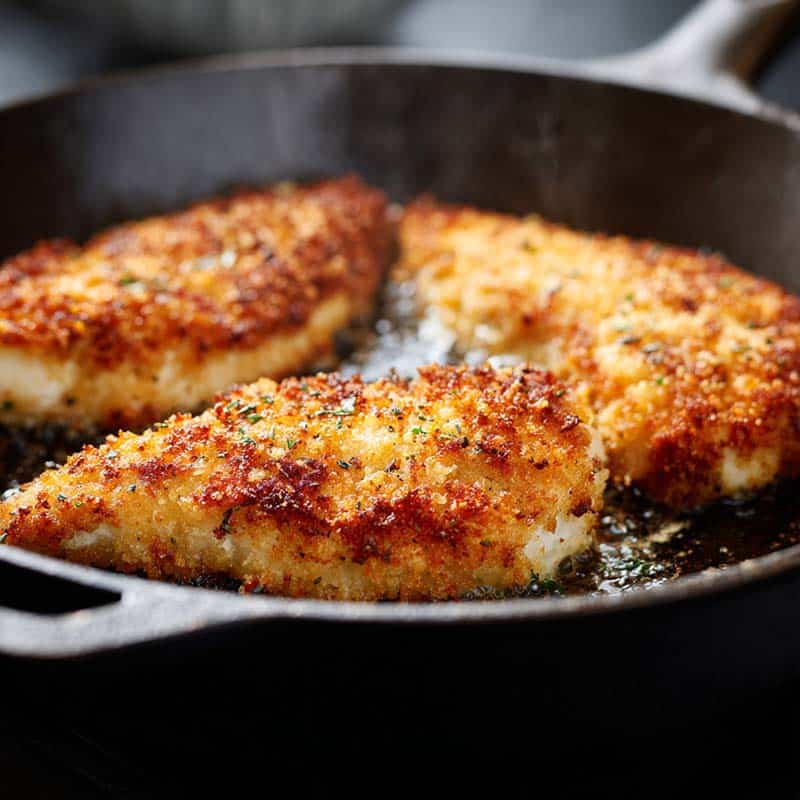 Chicken breasts frying for parmesan crusted chicken